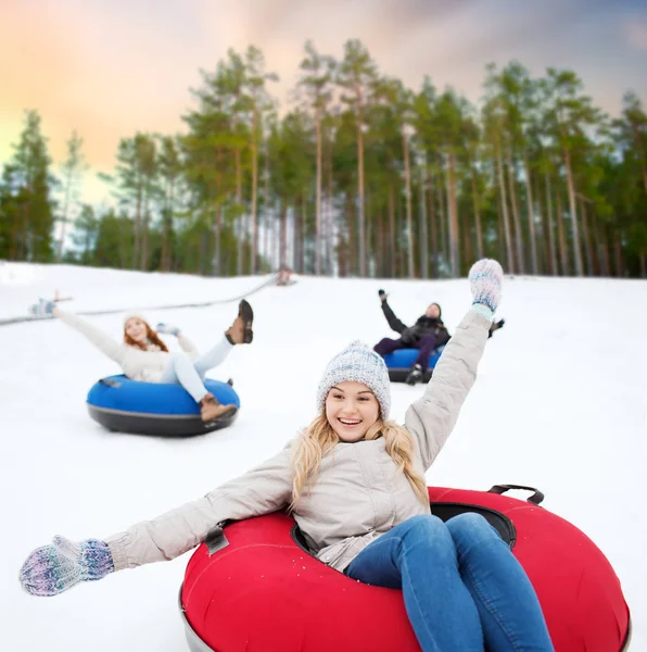 Amigos felizes deslizando colina abaixo em tubos de neve — Fotografia de Stock