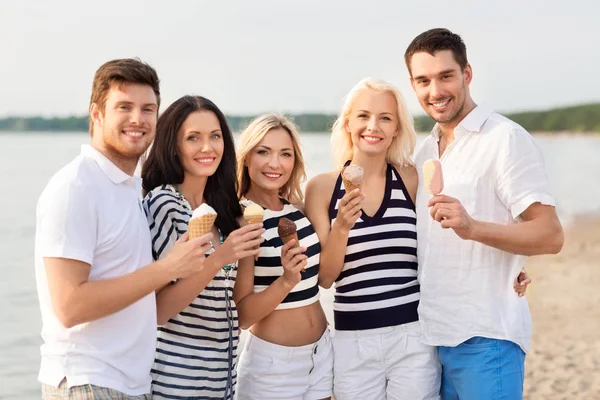 Amigos felices comiendo helado en la playa — Foto de Stock