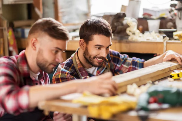 Carpenters measuring wooden board at workshop — Stock Photo, Image