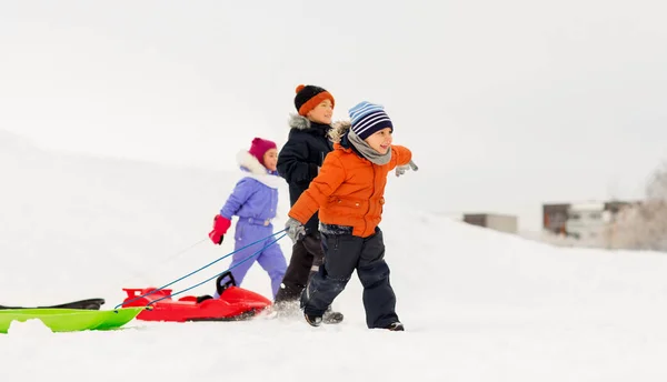 Bambini felici con le slitte in inverno — Foto Stock