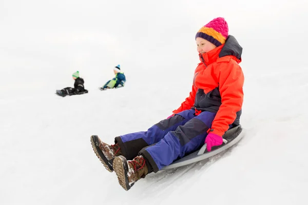 Bambini felici che scivolano sulla slitta giù per la collina in inverno — Foto Stock