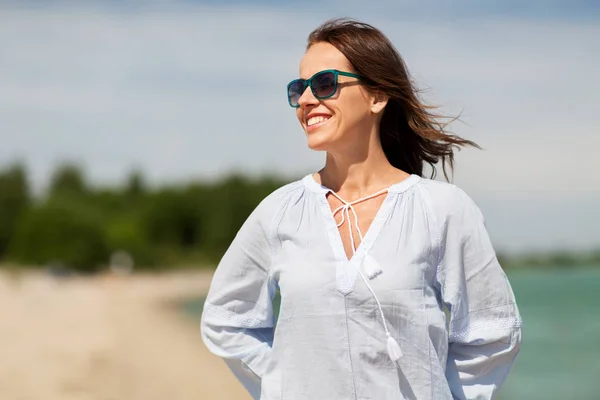 Счастливая улыбающаяся женщина в солнцезащитных очках на летнем пляже — стоковое фото