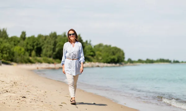 Szczęśliwy uśmiechający się kobieta spaceru wzdłuż plaży latem — Zdjęcie stockowe