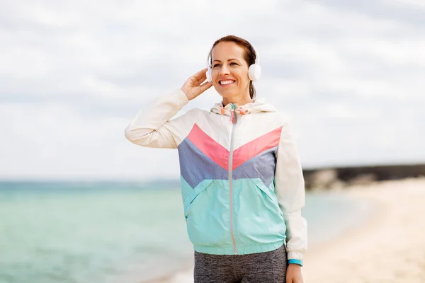Sportig kvinna med hörlurar på stranden — Stockfoto