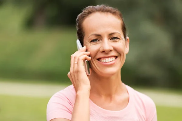 Mujer feliz llamando en el teléfono inteligente en el parque de verano —  Fotos de Stock