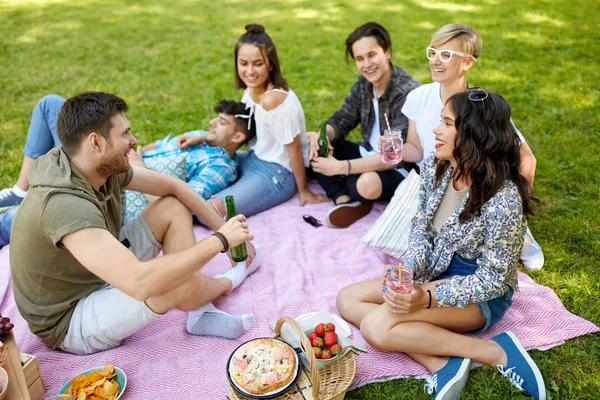 Glada vänner med drycker på picknick i sommaren park — Stockfoto