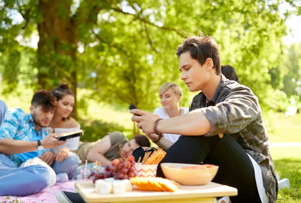 Człowiek za pomocą smartphone piknik z przyjaciółmi — Zdjęcie stockowe