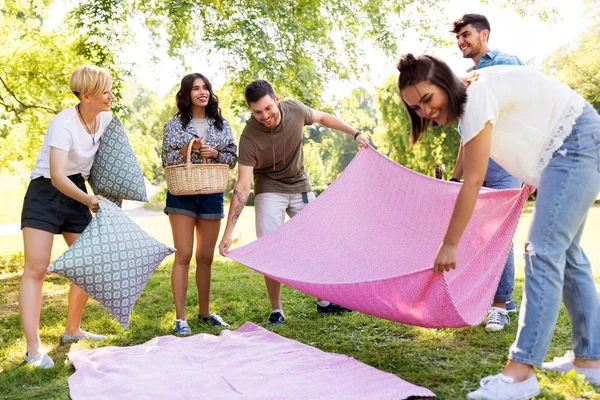 Amigos arrumando lugar para piquenique no parque de verão — Fotografia de Stock