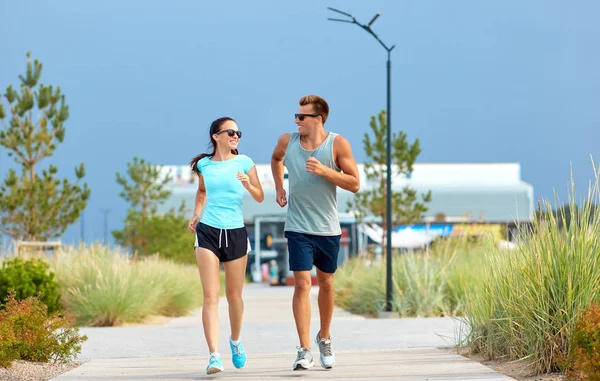 Pareja en ropa deportiva corriendo por la playa — Foto de Stock