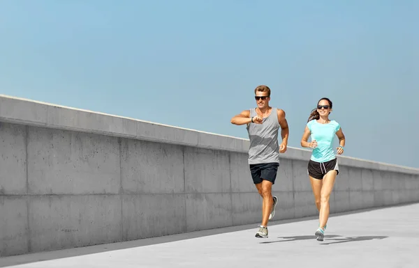 Couple in sports clothes running outdoors — Stock Photo, Image