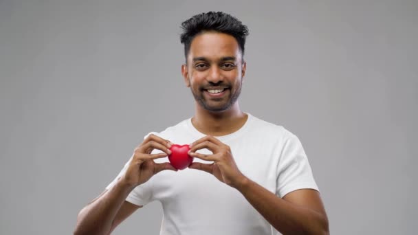 Индийский мужчина с красным сердцем на сером фоне — стоковое видео