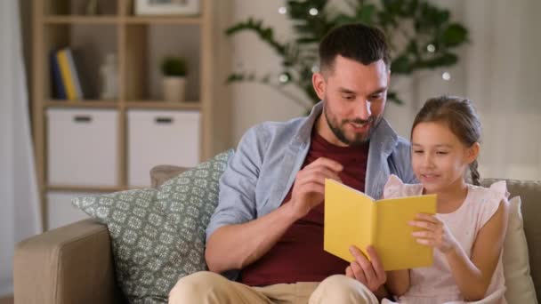 Happy father and daughter reading book at home — Stock Video