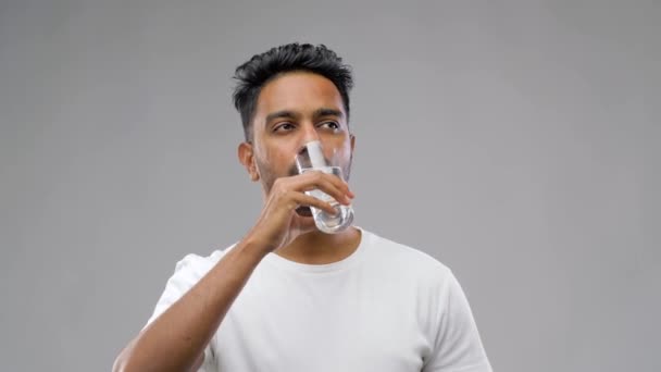 Счастливый молодой индиец пьет воду из стекла — стоковое видео