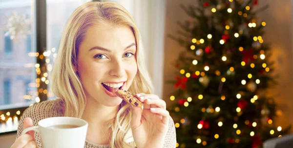 Frau mit Tee isst Plätzchen an Weihnachten zu Hause — Stockfoto