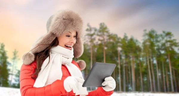 Kvinna i pälsmössa med TabletPC över vintern skog — Stockfoto