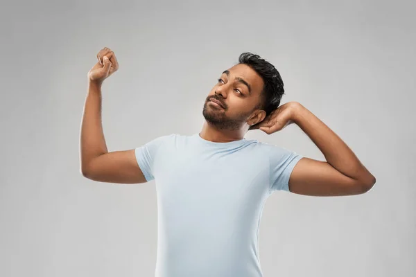 Indiase man die zich uitstrekt over grijze achtergrond — Stockfoto