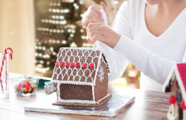 クリスマスのジンジャーブレッドの家を作る女性 — ストック写真