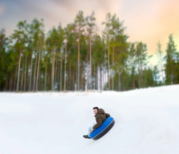 Heureux jeune homme glissant vers le bas colline sur le tube à neige — Photo