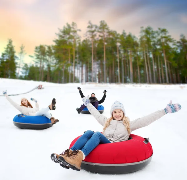 Szczęśliwy przyjaciółmi zjeżdżać hill na śnieg rury — Zdjęcie stockowe