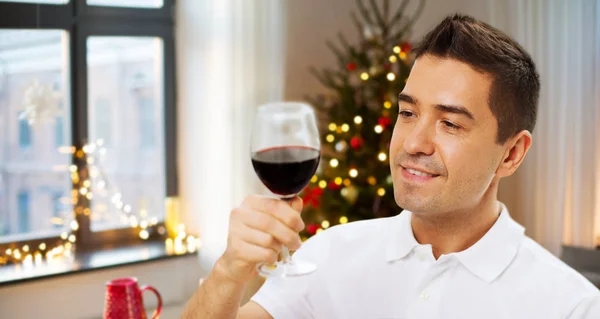 Happy man drinking red wine at home on christmas — Stock Photo, Image