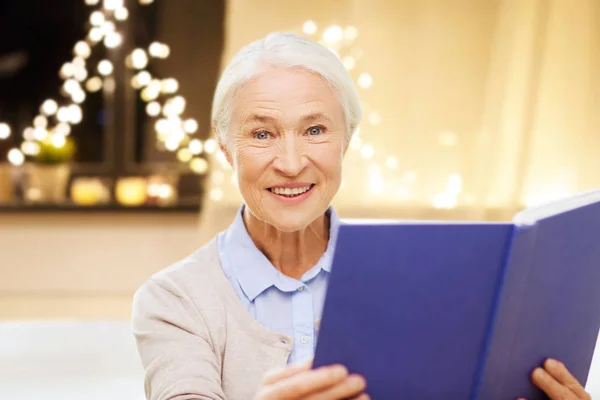 Donna anziana sorridente che legge il libro su Natale — Foto Stock