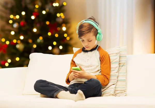 Menino com smartphone e fones de ouvido no Natal — Fotografia de Stock