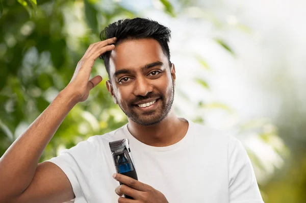 Uomo indiano sorridente con trimmer toccare i capelli — Foto Stock