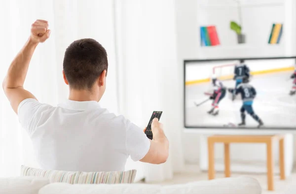 Homem assistindo jogo de hóquei no gelo na TV em casa Imagem De Stock