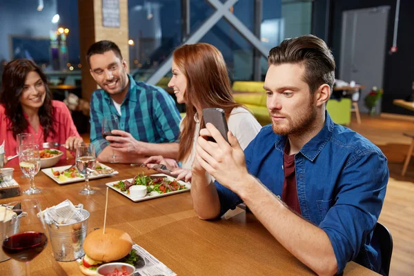 Обмен сообщениями на смартфоне в ресторане — стоковое фото