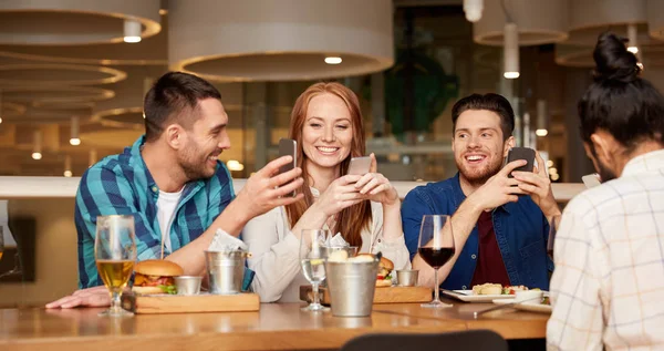 Happy friends with smartphones at restaurant — Stock Photo, Image