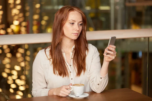 Žena s kávou a smartphone v restauraci — Stock fotografie