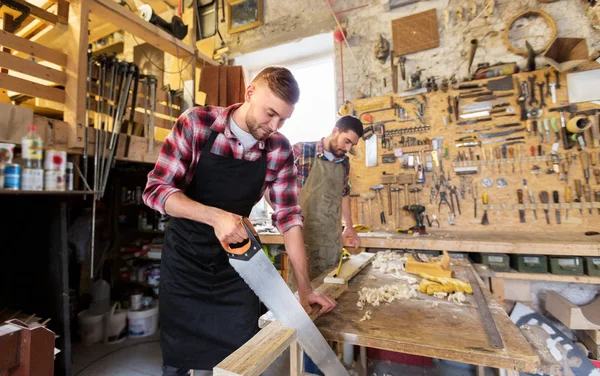 Falegnami che lavorano con sega e legno in officina — Foto Stock