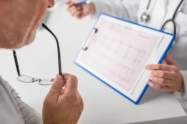 Senior man and doctor with cardiogram at hospital — Stock Photo, Image