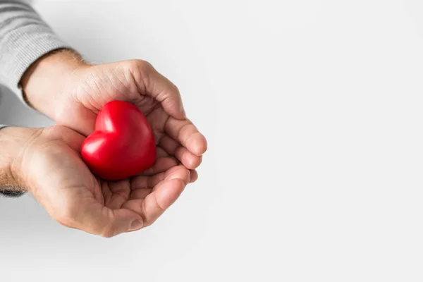 Kupade senior mannen händerna med rött hjärta form — Stockfoto