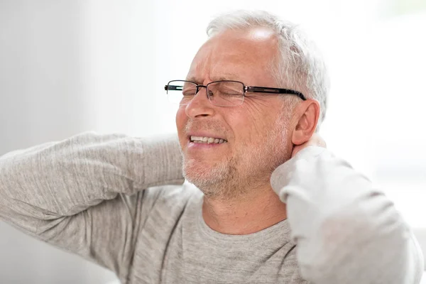 Homem idoso que sofre de dor de pescoço em casa — Fotografia de Stock