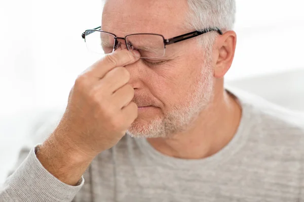 Äldre mannen i glasögon massera näsbrygga — Stockfoto