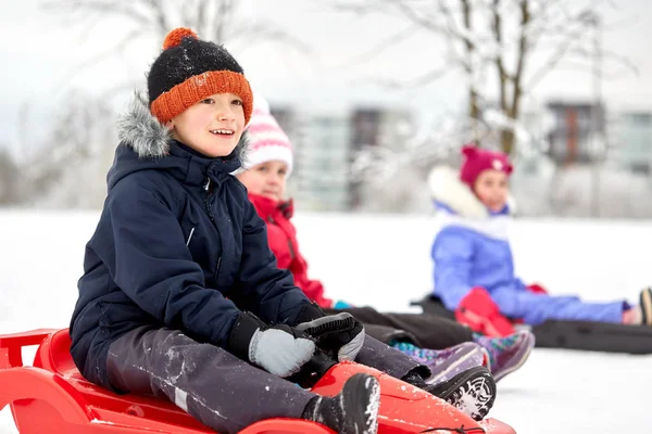 Счастливые дети катаются на санках зимой — стоковое фото