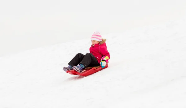 Happy little girl sliding down on sled in winter — Stock Photo, Image
