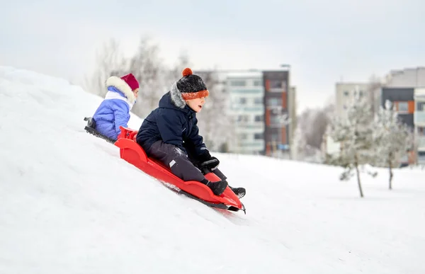 Kinderen glijden op sleeën bergafwaarts sneeuw in de winter — Stockfoto