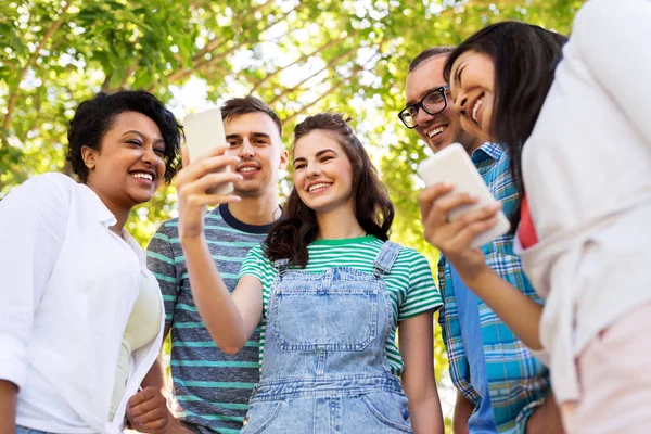 Glada vänner med smartphone på sommarparken — Stockfoto
