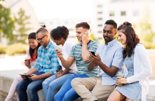 Vrienden met smartphones opknoping in de zomer — Stockfoto