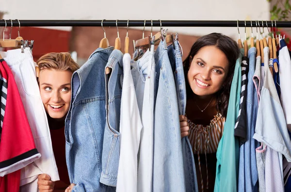 Женщины веселятся на вешалке магазина винтажной одежды — стоковое фото