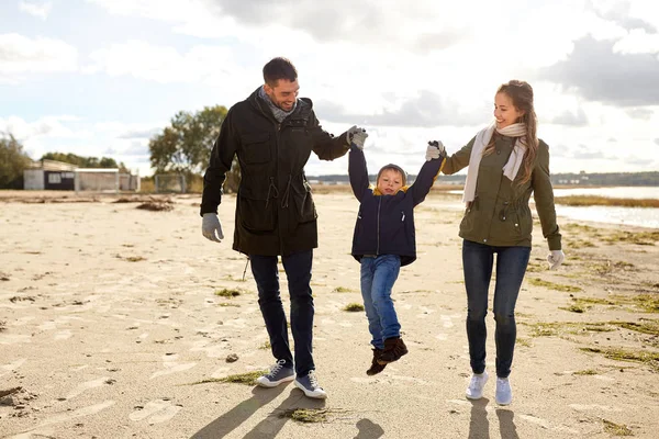Família feliz andando ao longo da praia de outono — Fotografia de Stock