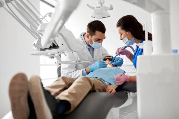 Dentista tratar dentes de criança na clínica odontológica — Fotografia de Stock