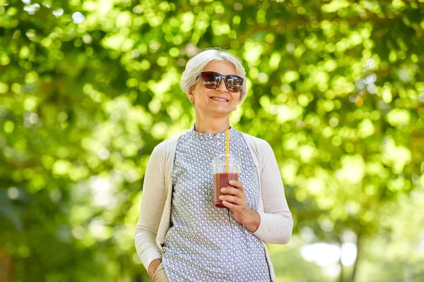 Senior Kvinna dricka avhämtning skaka på park — Stockfoto