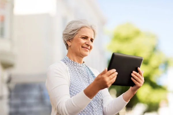 Smiling senior woman with tablet pc on city street — Stock Photo, Image