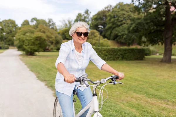 Szczęśliwa kobieta senior jazdy na rowerze w lato park — Zdjęcie stockowe