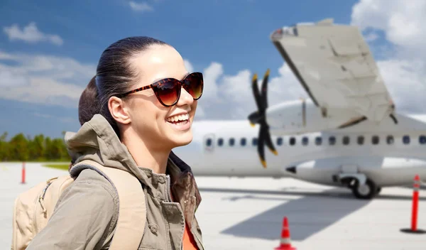 Junge Frau mit Rucksack über Flugzeug auf Flugplatz — Stockfoto