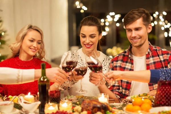 Amigos felizes bebendo vinho tinto na festa de Natal — Fotografia de Stock