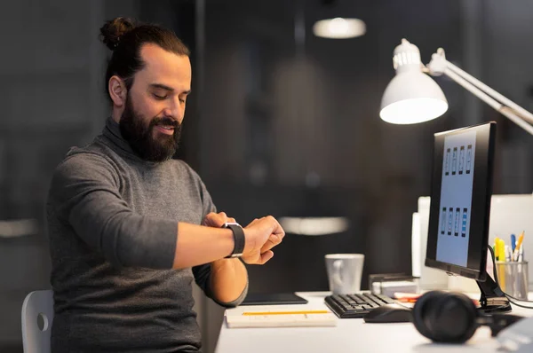 Homme avec smartwatch et ordinateur au bureau de nuit — Photo